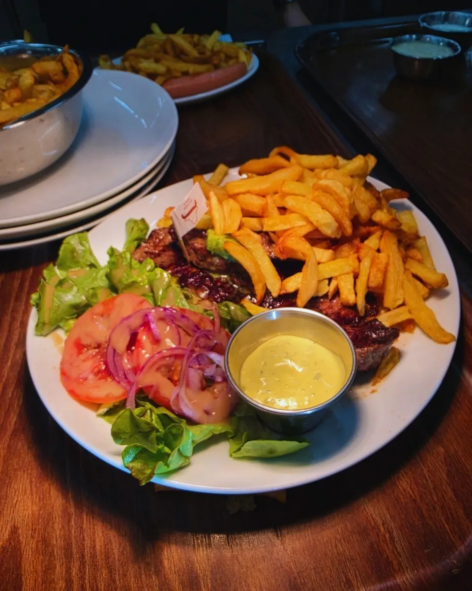 Assiette de bœuf grillé, frites maison, salade et coupelle de béarnaise avec drapeau de cuisson.