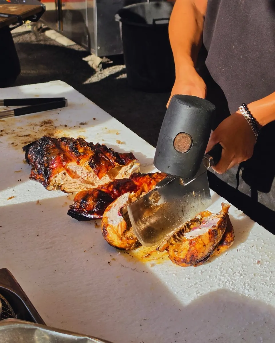 La découpe du cochon grillé au couperet et au maillet, devant les clients
