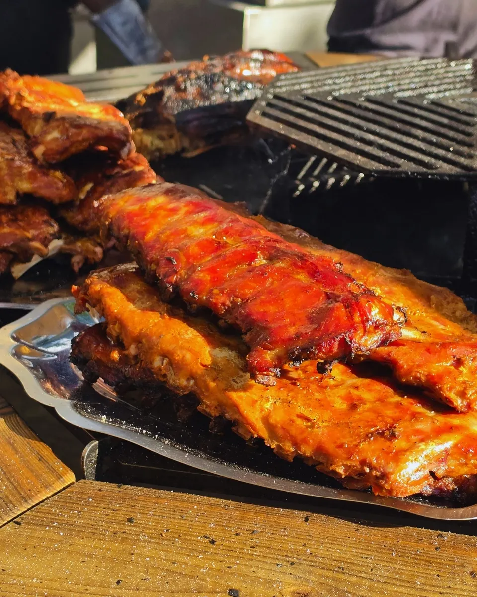 Le rôti de porc grillé est tranché au couperet et au maillet, croûte caramélisée en pleine lumière.
