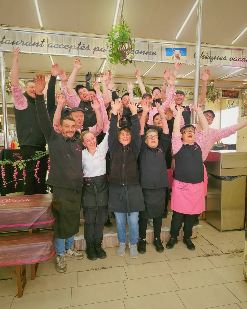 Toute l'équipe de la Maison Hector, bras levés et sourire aux lèvres, réunie devant la brasserie
