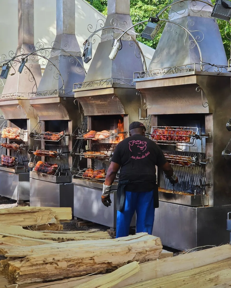 Quatre rôtissoires où des cochons entiers tournent à la broche au-dessus des flammes et des bûches de hêtre