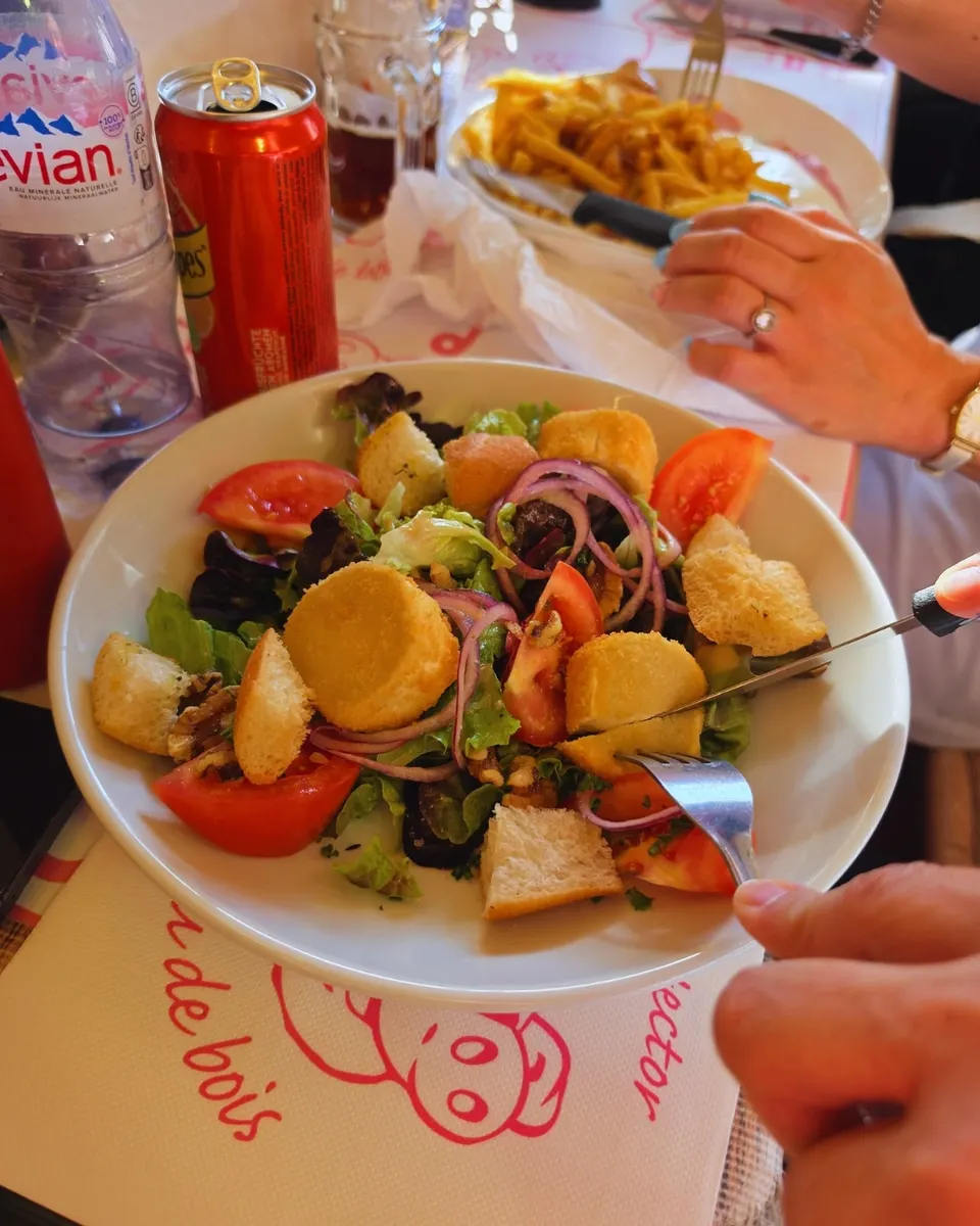 Salade de chèvre chaud pané dégustée à table sur la nappe papier au cochon Hector.