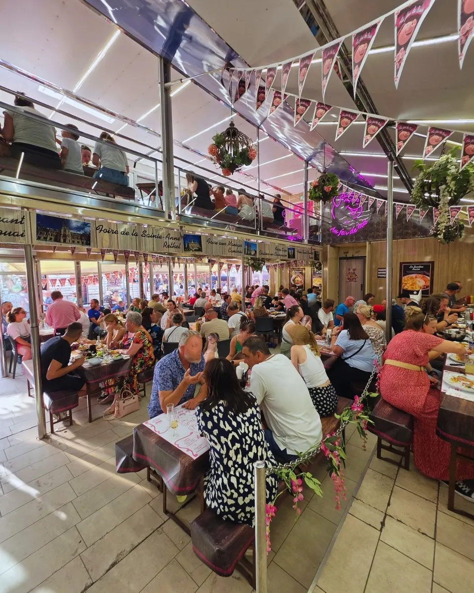 La salle comble du restaurant éphémère sur deux niveaux, fanions roses au cochon, néon et banderoles des foires.