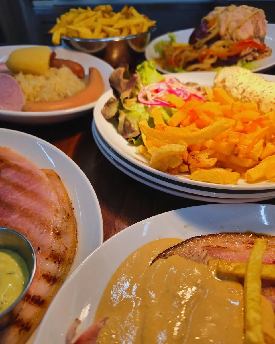 Table couverte d'assiettes généreuses : frites, choucroute, jambon grillé et effiloché de porc.