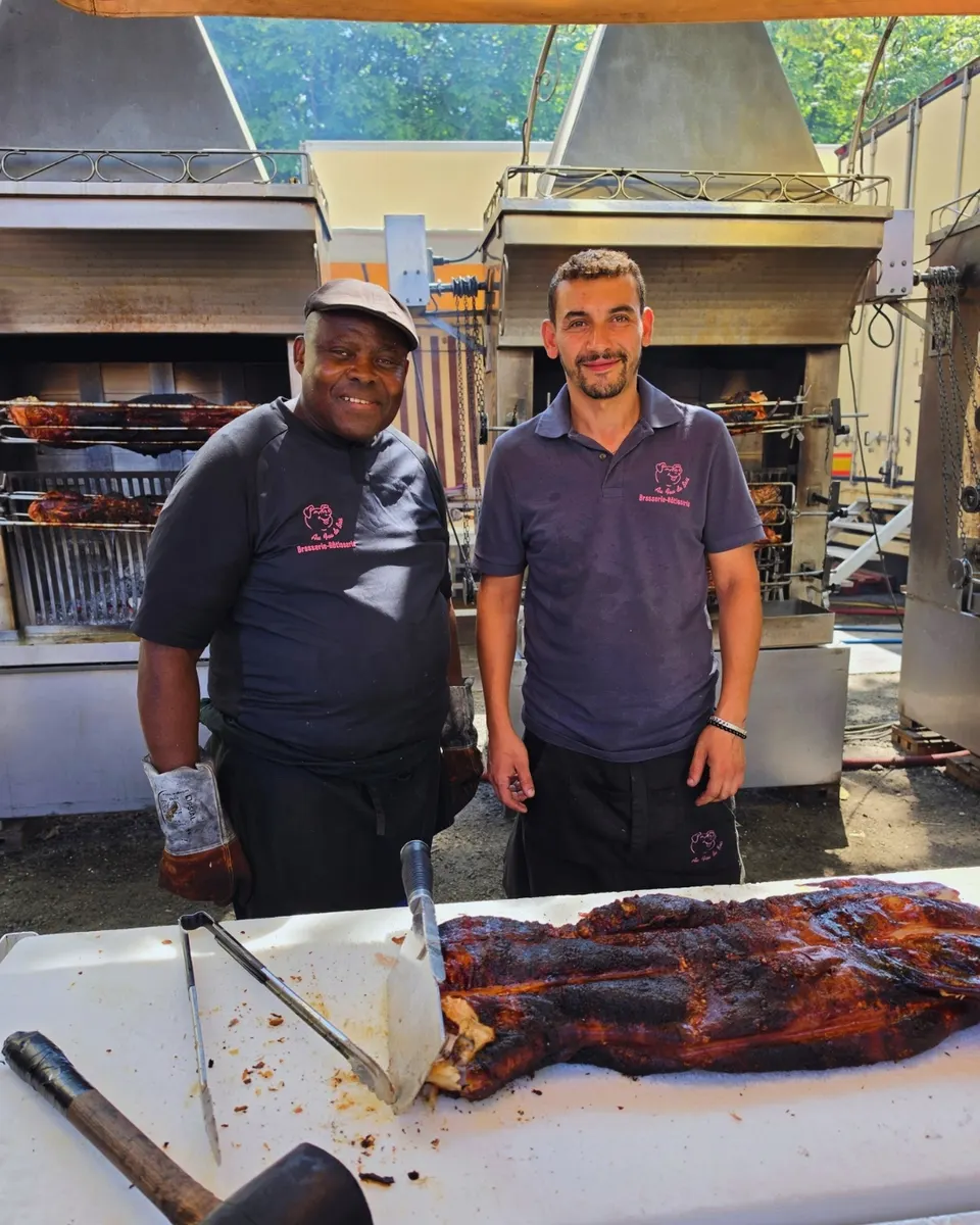 Le trio de rôtisseurs pose pendant la découpe du cochon rôti entier, couperet en main.