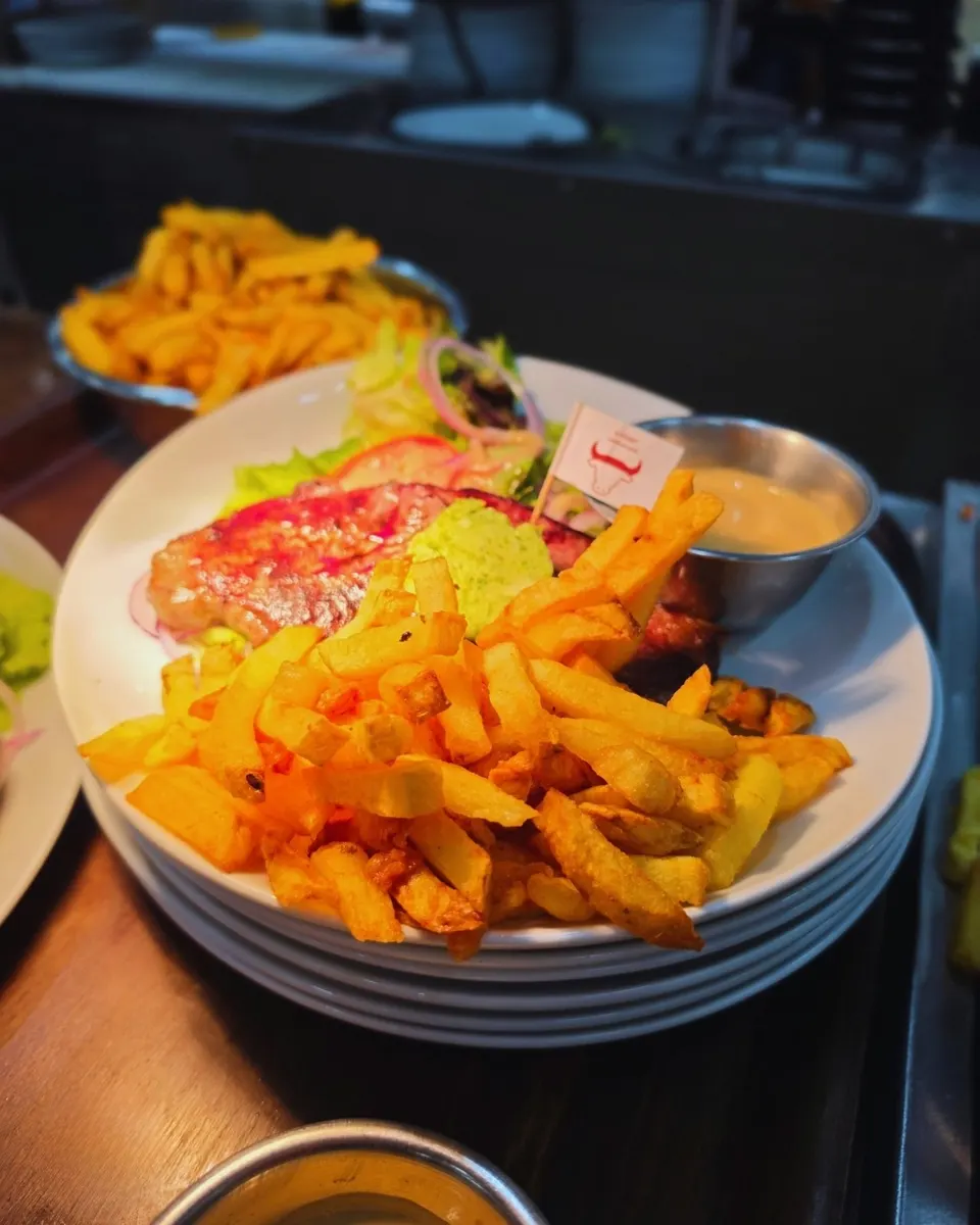 Pièce de viande grillée au beurre aux herbes, fanion de cuisson, salade fraîche et frites maison.